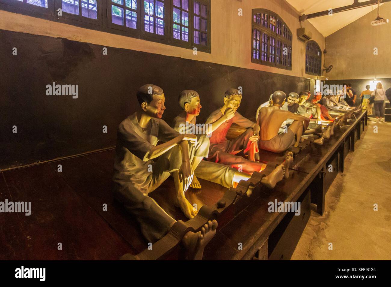 Eine große Kunstinstallation im Innenraum zeigt Reihen menschlicher Figuren in Bewegung unter warmem Licht hinter reflektierendem Glas. Stockfoto