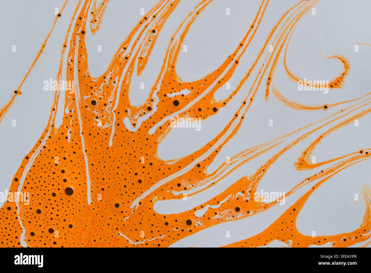 Verteilung von orangefarbener Flüssigfarbe, die Wellenmuster auf einem hellen Hintergrund bildet, Kopierraum Stockfoto