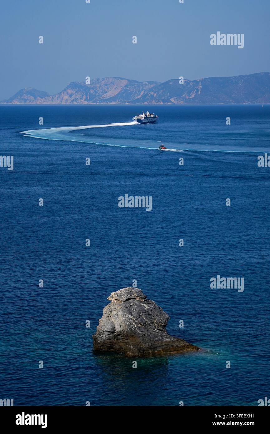 Fähre und Pilotenboot passieren einen Felsen im Meer, Skopelos, Griechenland Stockfoto