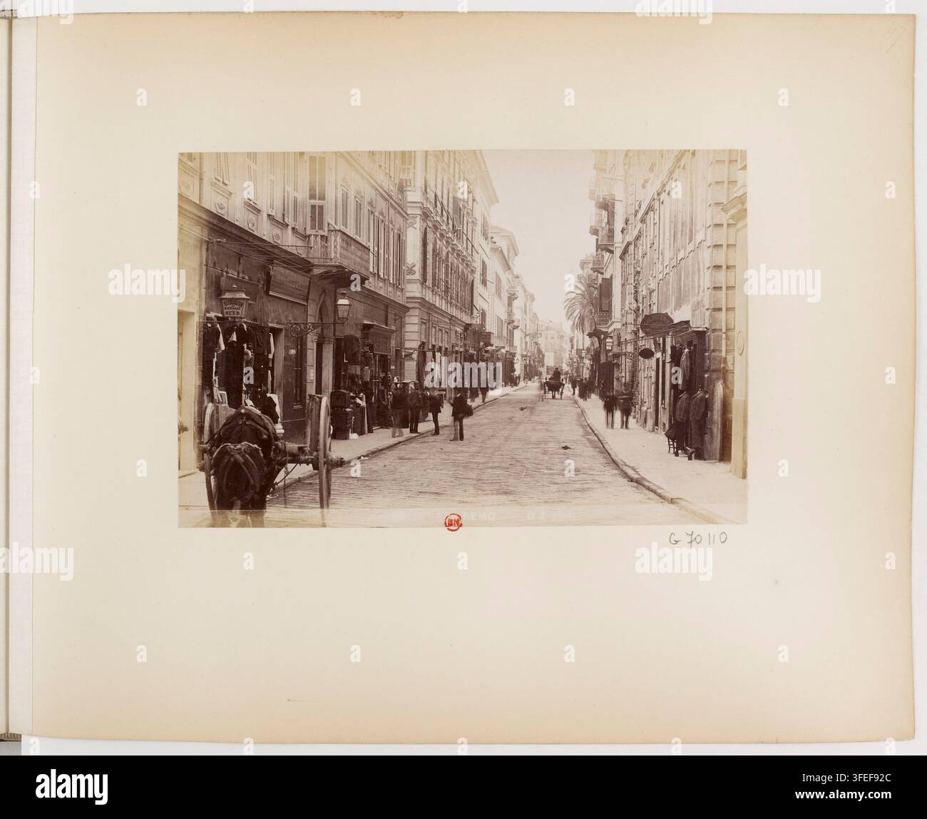 Eine Straßenszene in Avignon, Frankreich, von Jean Gilletta im Jahr 1892, die Gebäude, eine Kopfsteinpflasterstraße und Figuren zeigt, die in der Nähe von Ladenfronten und einem Pferdewagen stehen oder gehen. Stockfoto