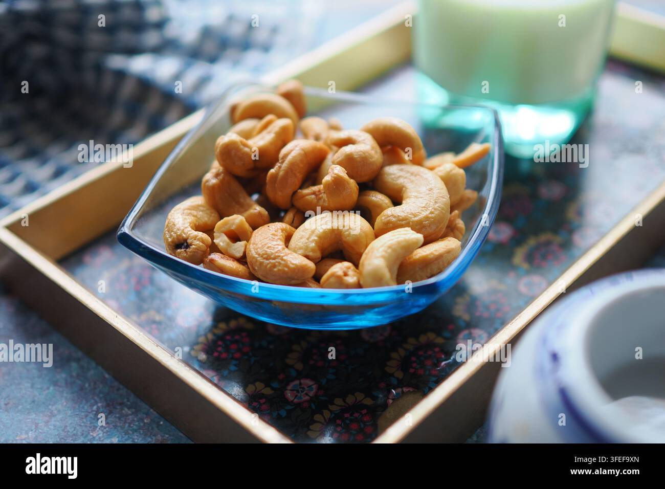 Cashewnüsse in einer Glasschale auf einem Holztablett Stockfoto