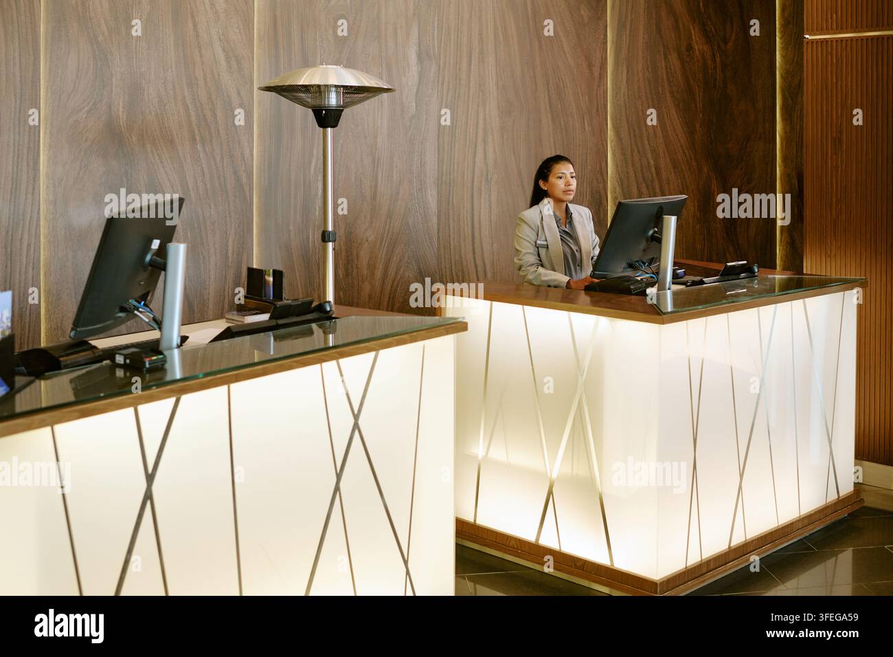 Hispanische Empfangsdame arbeitet an einem Computer in der Hotellobby Stockfoto