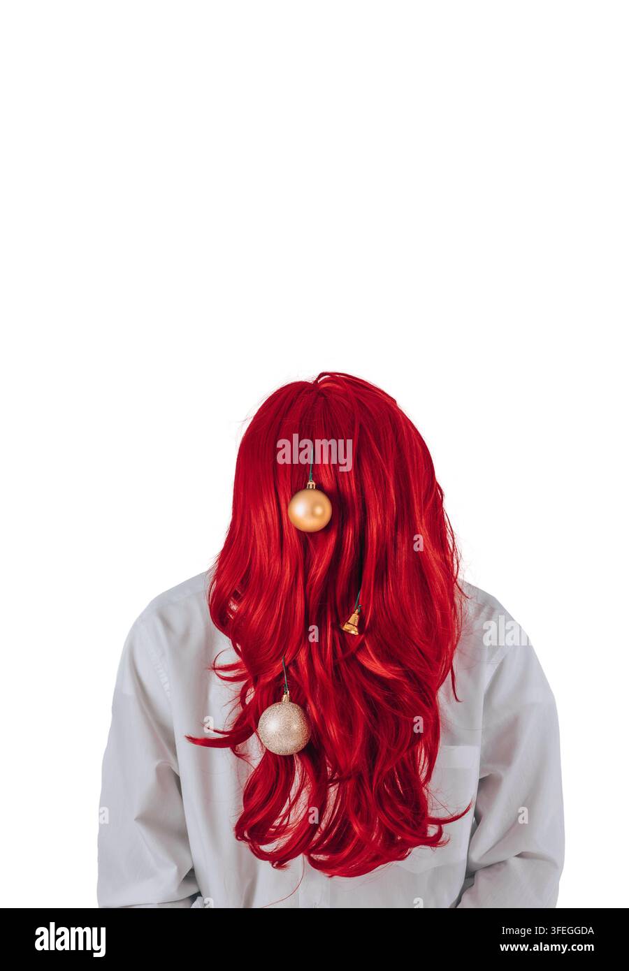 Person, die ihr Gesicht hinter einer langen roten Perücke versteckt, die mit Weihnachtsschmuck verziert ist, isoliert auf weißem Hintergrund. Kreative festliche Frisur und humorvolle Feiertagsstimmung Stockfoto