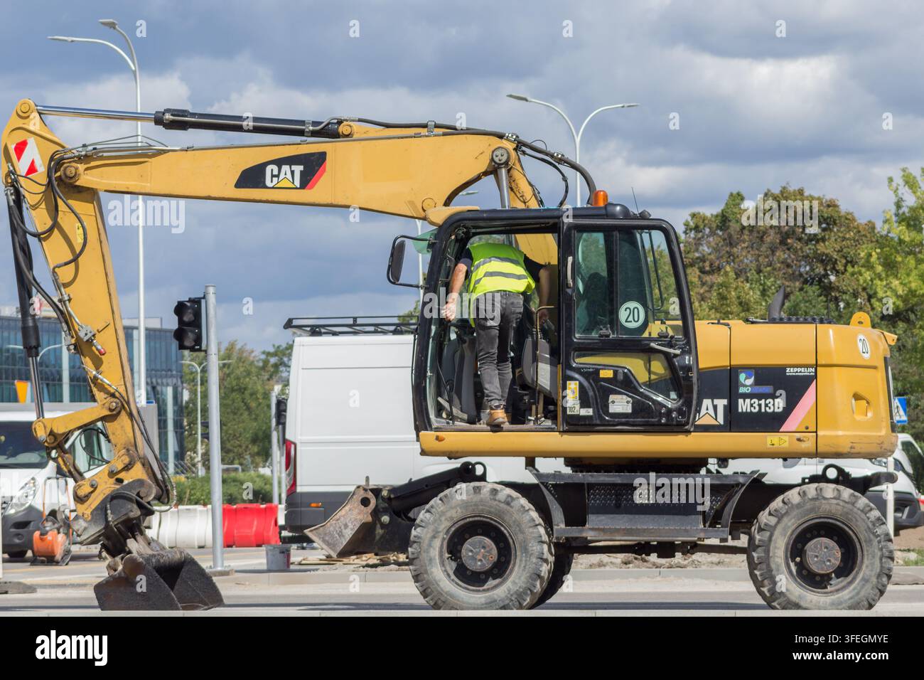 Caterpillar CAT-Radbagger mit einem Bauarbeiter während der Straßenrekonstruktion in einem städtischen Gebiet Stockfoto