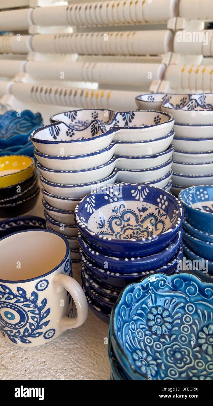 Blaue und weiße griechische Souvenirs Beschreibung: Bunte handgefertigte griechische Keramiksouvenirs mit Olivenmotiven, die traditionelle mediterrane Handwerkskunst präsentieren. - Smartphone-aufgenommenes Stockfoto