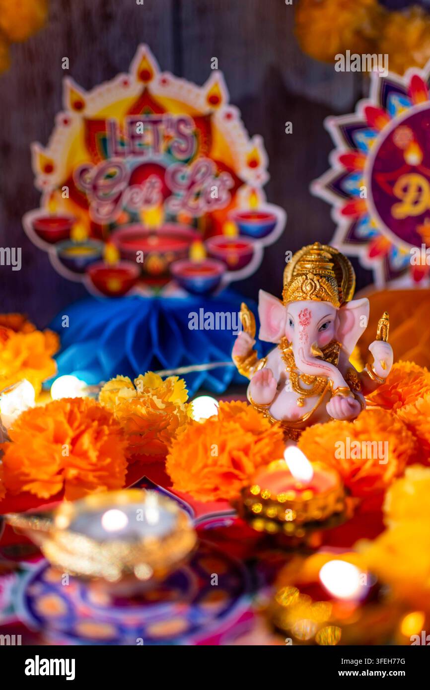 Ganesha-Idol, das zwischen Marigold-Blumen, beleuchteten Diyas und festlichen Dekorationen während Diwali sitzt Stockfoto