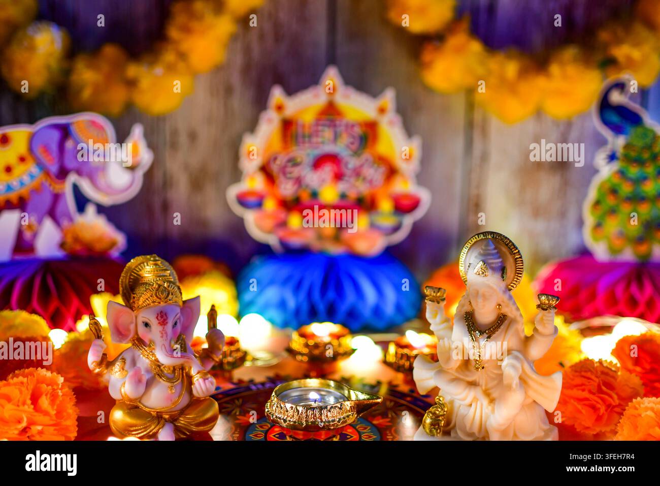 Ganesha- und Lakshmi-Gottheiten, die während Diwali mit Ringelblumen-Girlanden und leuchtenden Diyas geschmückt sind Stockfoto