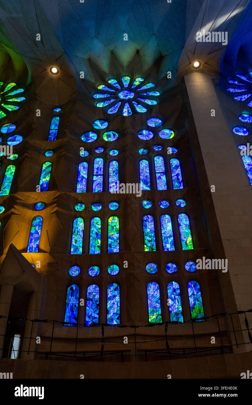 Barcelona, Spanien 01.09.2026 Buntglas füllt die Kirchenwand mit einem Lichtmuster, das blaue, grüne und violette Töne in kreisförmigen und schmalen Fenstern vermischt Stockfoto