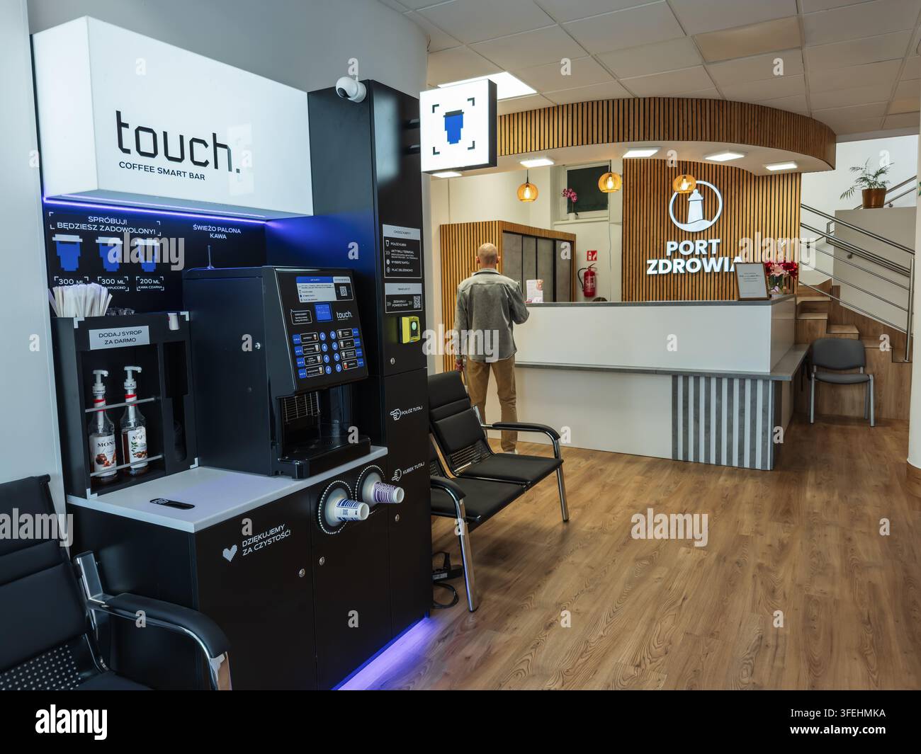 Danzig, Polen – 14. Juli 2026: Moderner Bürowartebereich in einem privaten Krankenhaus mit einem automatisierten Kaffeeständer und Empfangstisch, der professionelles Innendesign und Komfort betont Stockfoto