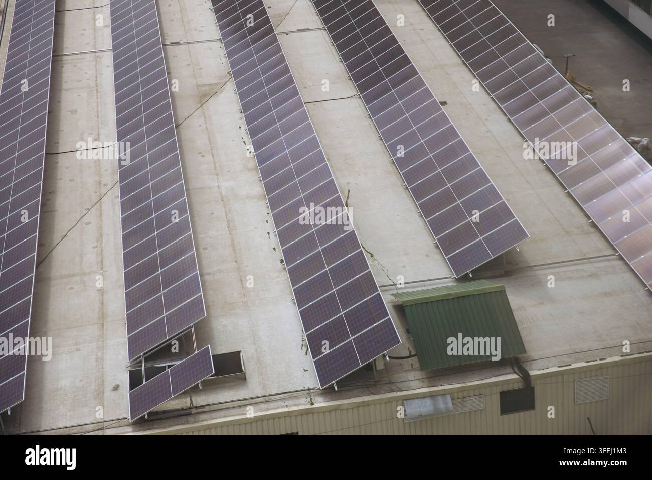 Luftaufnahme von Solarmodulen, die auf einem flachen Industrie-Dach installiert sind, Reihen von Photovoltaik-Panelen für die Erzeugung erneuerbarer Energie in einer städtischen Umgebung Stockfoto