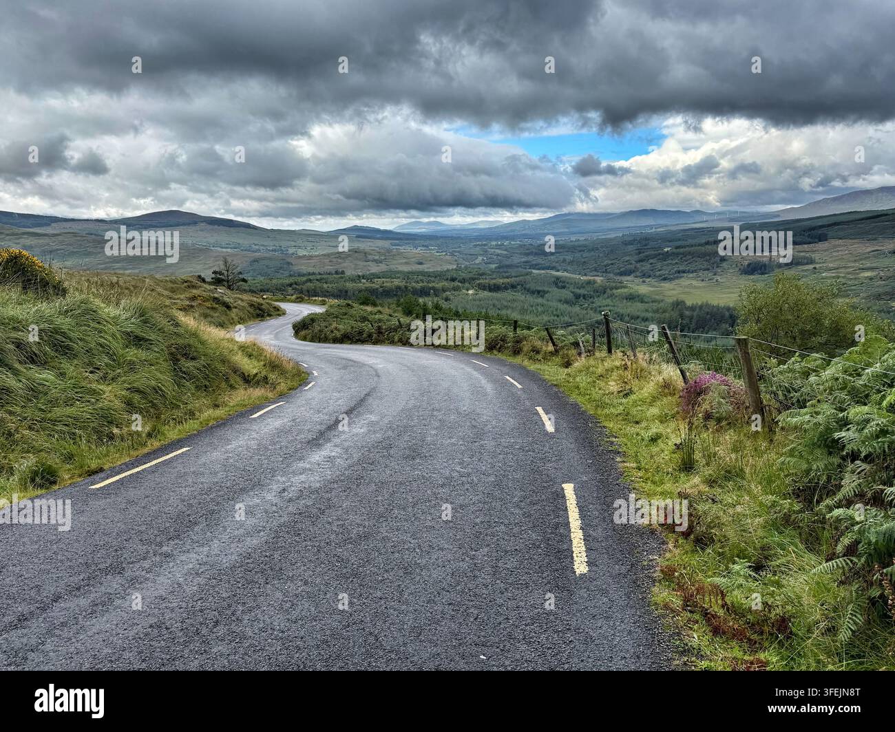 Eine Aussicht von der L4010-Straße kurz nach dem Ballaghisheen-Pass durch die Berge in Richtung Nordosten nach Killarney, Grafschaft Kerry, Irland. - Smartphone-aufgenommenes Stockfoto