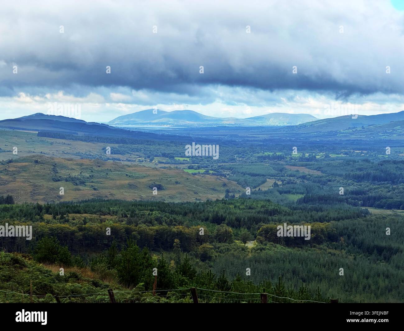 Eine Aussicht von der L4010-Straße kurz nach dem Ballaghisheen-Pass durch die Berge in Richtung Nordosten nach Killarney, Grafschaft Kerry, Irland. - Smartphone-aufgenommenes Stockfoto
