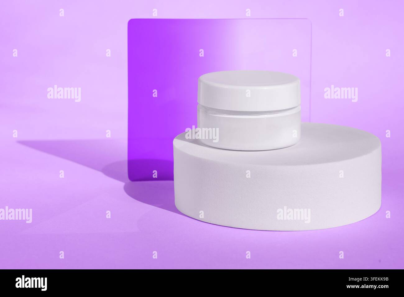 Kosmetisches Hautpflegeglas auf minimalistischem Podest mit lila Hintergrund Stockfoto