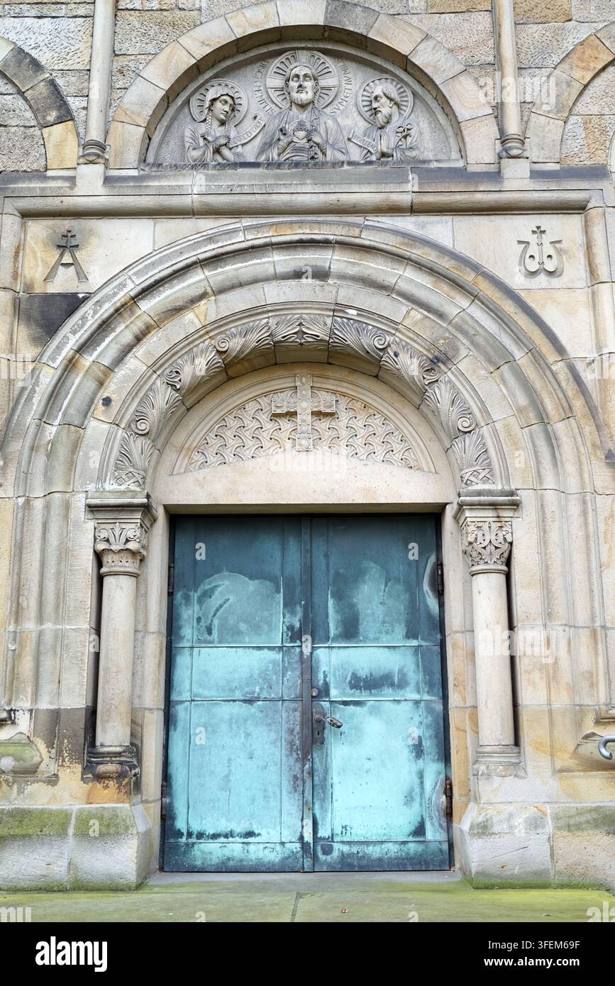 Rheine, Deutschland - 15. Feb 2022 - Seiteneingang der St.-Antonius-Basilika. Ein Portal mit dem charakteristischen figürlichen Tympanon. Zu sehen ist Christus in der Stockfoto