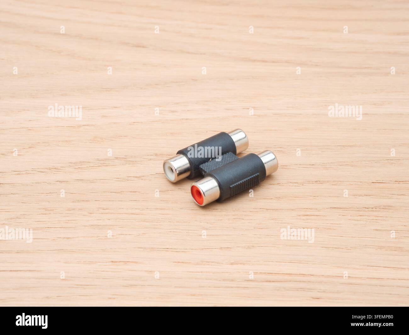 RCA-Buchse-zu-Buchse-Adapter – Zwei Audio-Video-RCA-Buchse-zu-Buchse-Kupplungen, eine mit rotem Anschluss und eine mit weißem Anschluss, die auf einem l ruhen Stockfoto