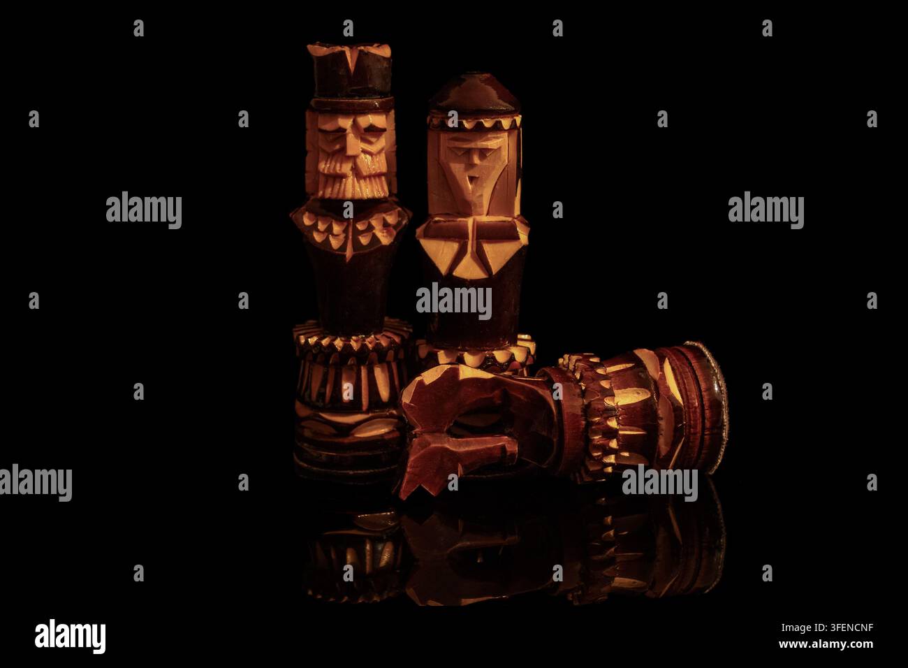 Geschnitzte Holzschachfiguren mit einem gefallenen Ritter auf schwarzem Hintergrund Stockfoto