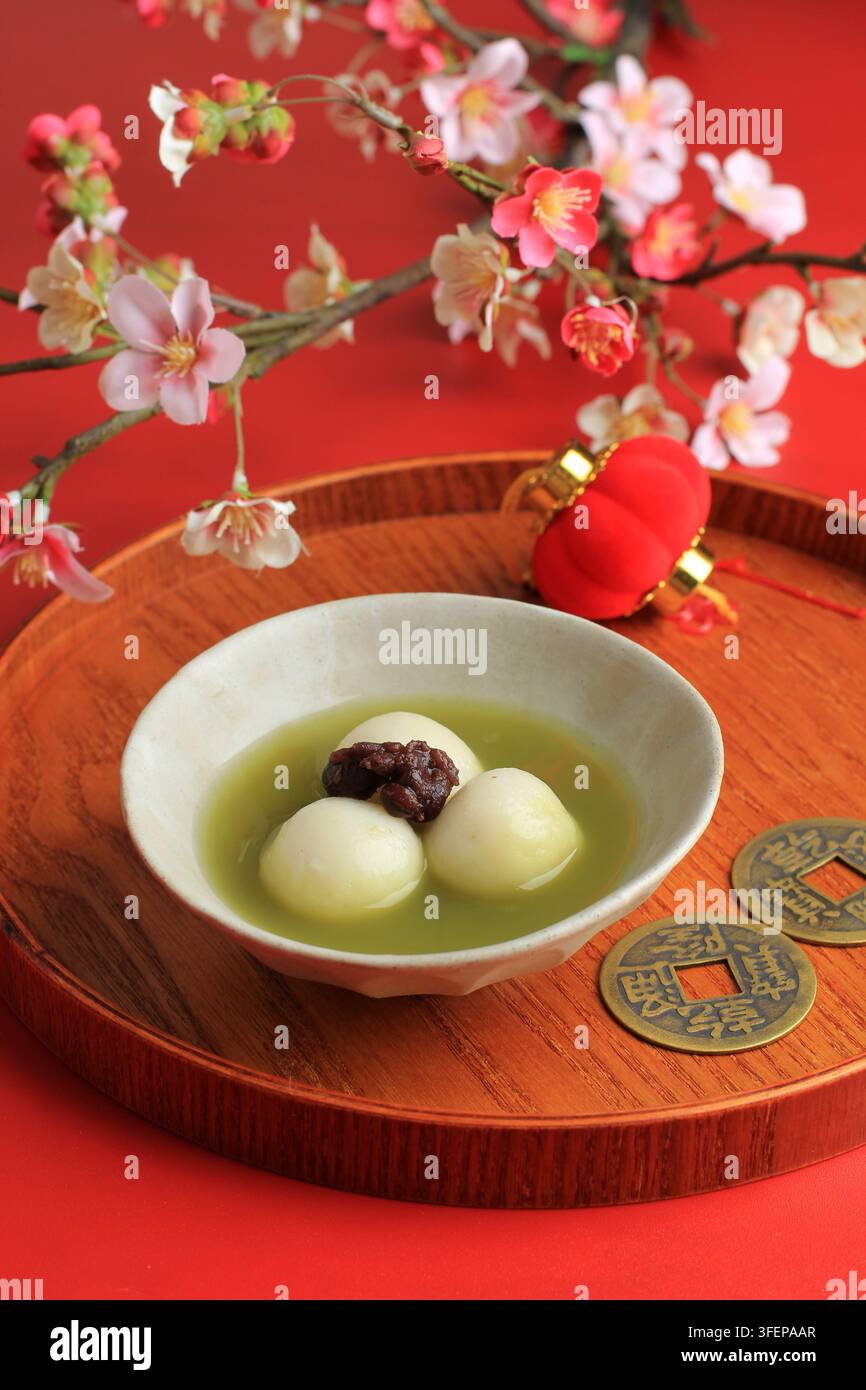 Grüner Tee Big Tangyuan und Matcha-Suppe auf Holztablett über rotem Tisch. Stockfoto