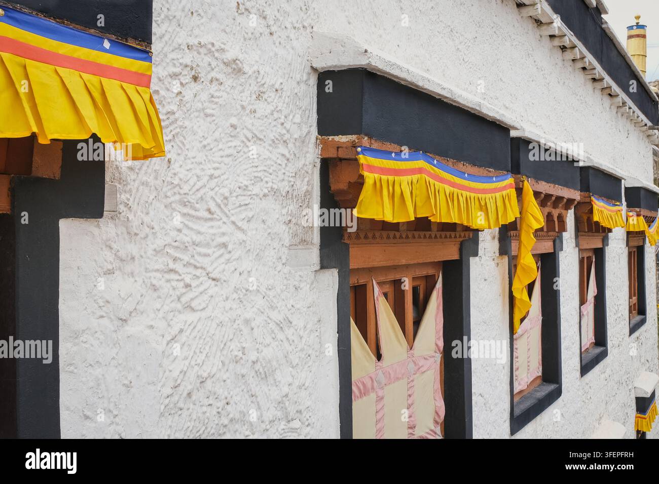 Traditionelle Fenster, bunte Textildekoration an einer weiß getünchten Wand im Kloster Ladakh, Indien, buddhistische Architektur der Himalaya-Region. Stockfoto