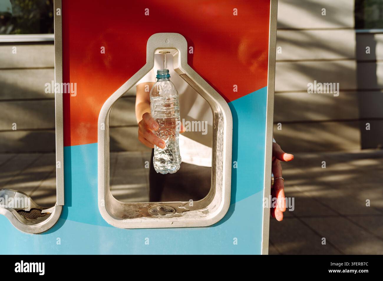 Eine Person füllt eine Plastikflasche mit Trinkwasser, während sie im Sommer in der Stadt unterwegs ist. Trinkwasser-Füllstation Stockfoto