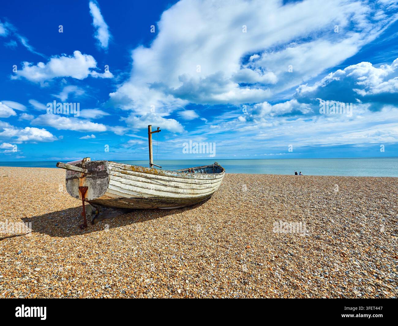 Verwittertes Holzfischerboot auf Kiesstrand in Aldeburgh bei ruhigem Meer unter blauem Himmel und vereinzelten Wolken Stockfoto