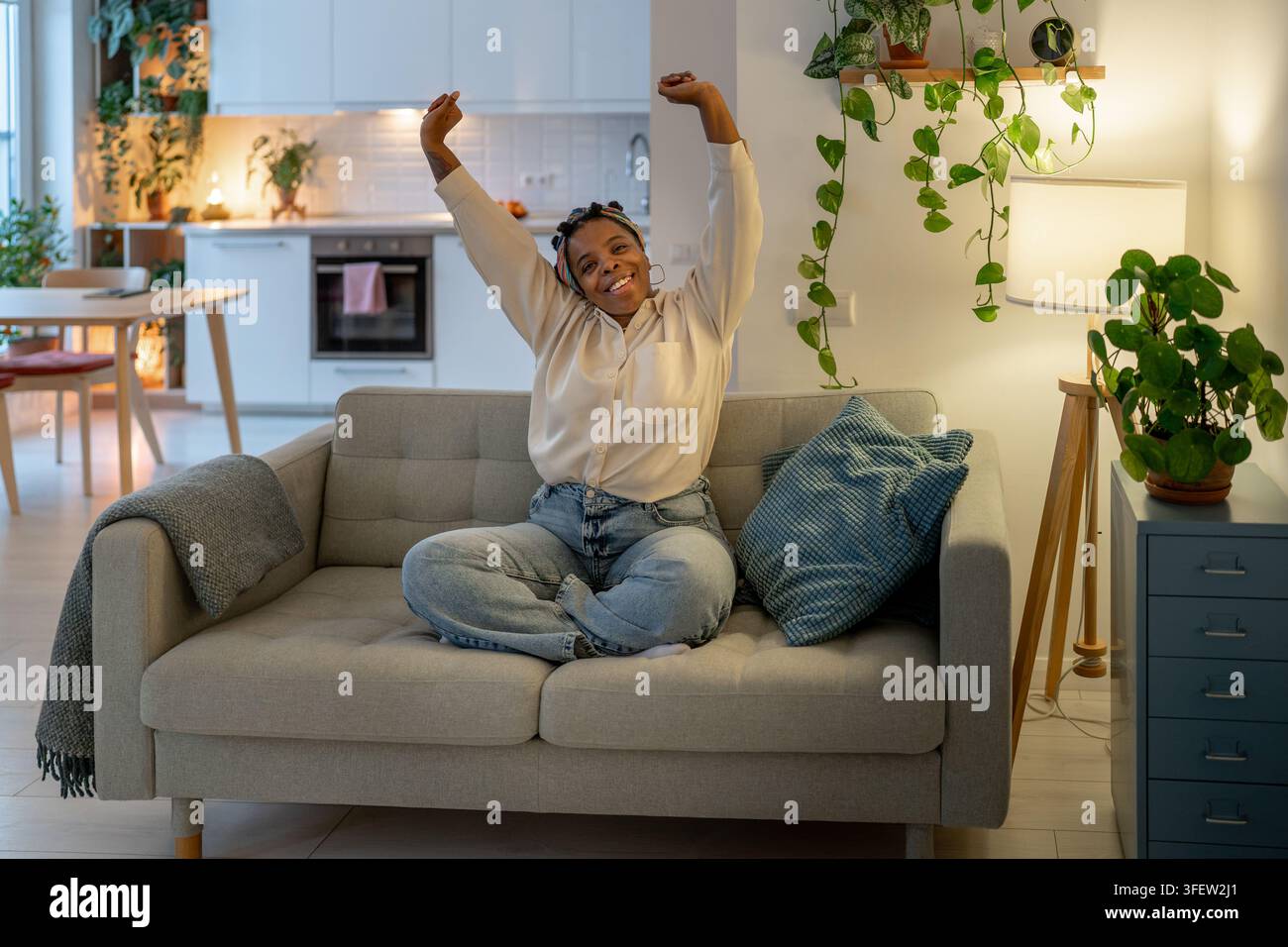 Fröhliche schwarze Frau, die nach der Meditation zu Hause die Arme streckt, fühlt sich erfrischt, entspannt, voller Energie. Stockfoto
