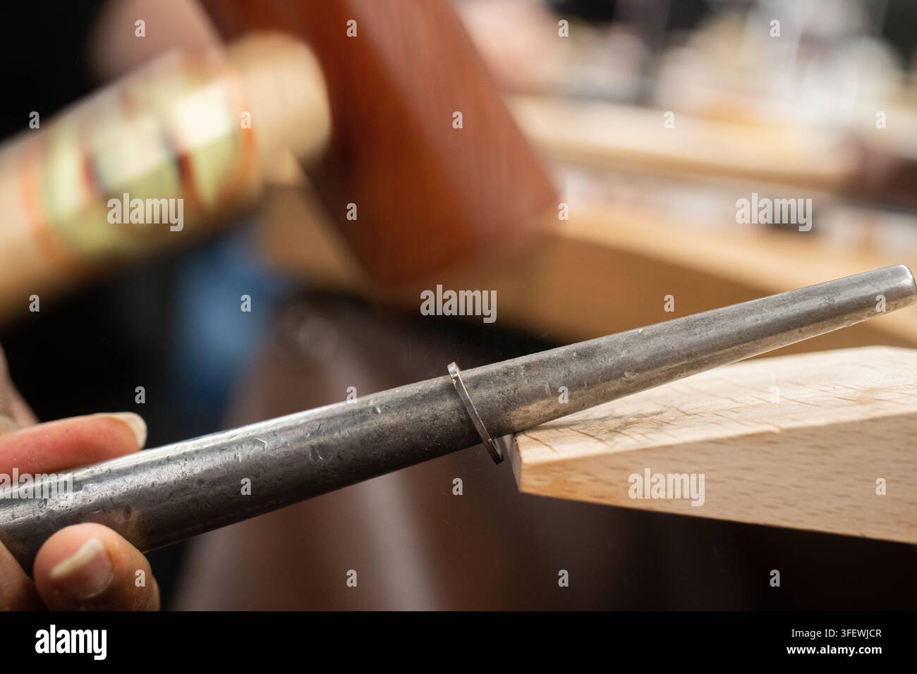 Ein Juwelier verwendet einen Hammer, um einen Ring auf einer Rundschleifspindel zu formen und feinen Schmuck in Hatton Garden, dem historischen Schmuckviertel Londons, herzustellen. Stockfoto