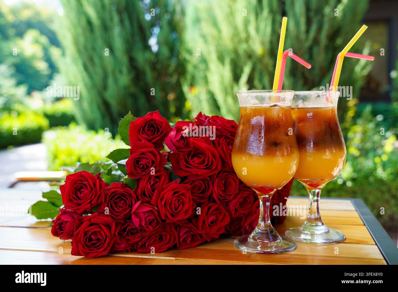 Getränke und Rosen auf einem Tisch in einem Garten bei warmem Wetter Stockfoto