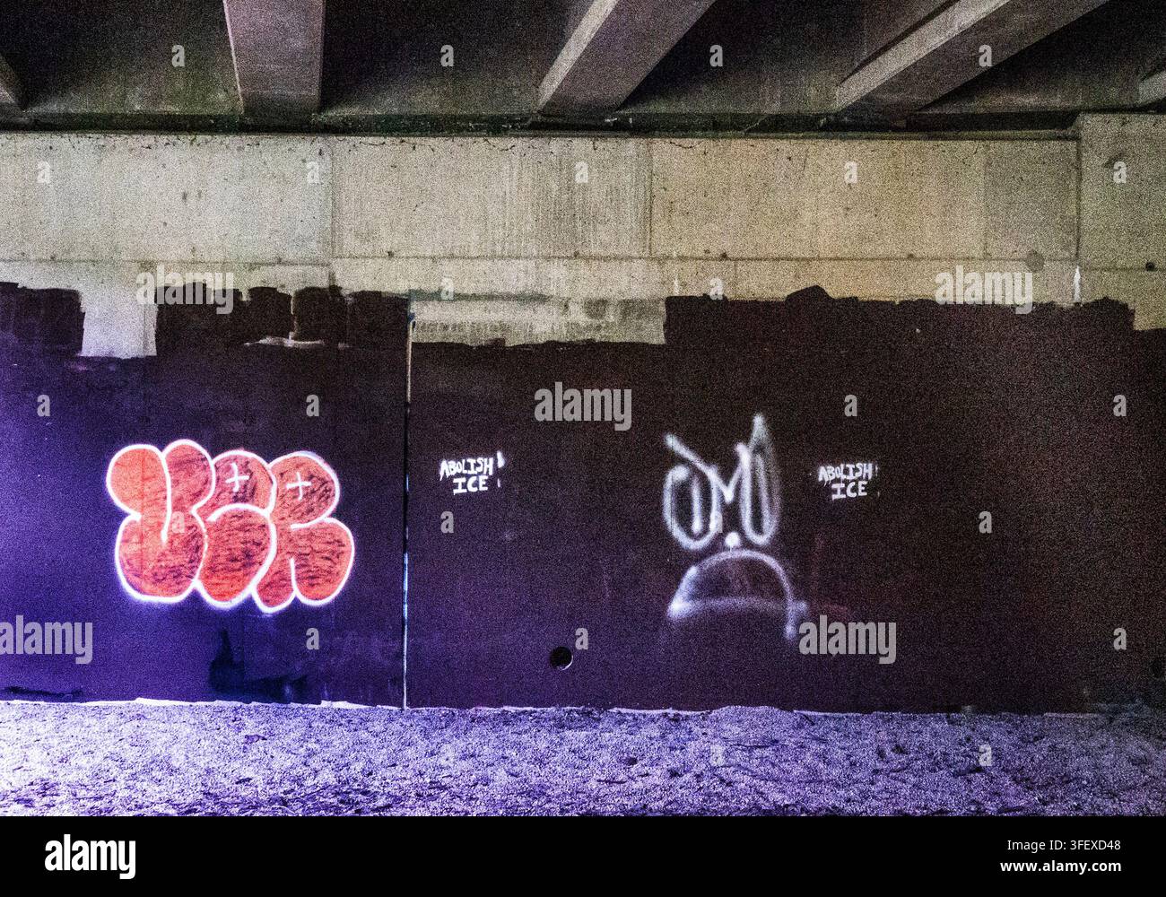 Eine Betonüberführung mit gesprühtem Graffiti, darunter ein helloranges Bubble-Letter-Piece links und eine stilisierte weiße Cartoon-Figur Stockfoto