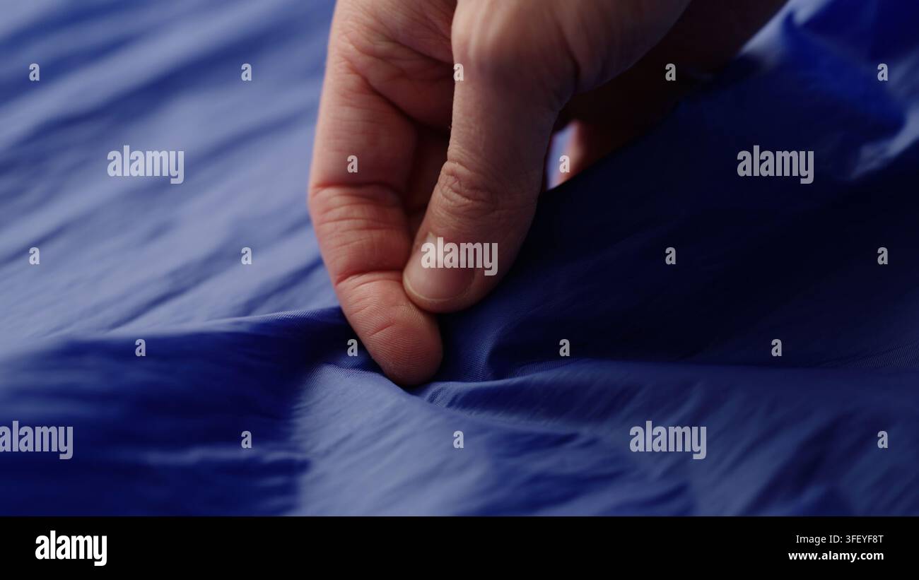 Männerhand prüft blauen Kunststofftaschenstoff Stockfoto