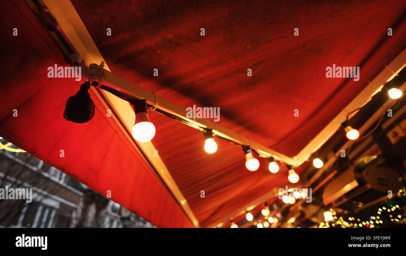 Helle Lichterketten beleuchten eine rote Zeltkonstruktion im Freien bei Nacht im Zentrum von Brüssel Stockfoto