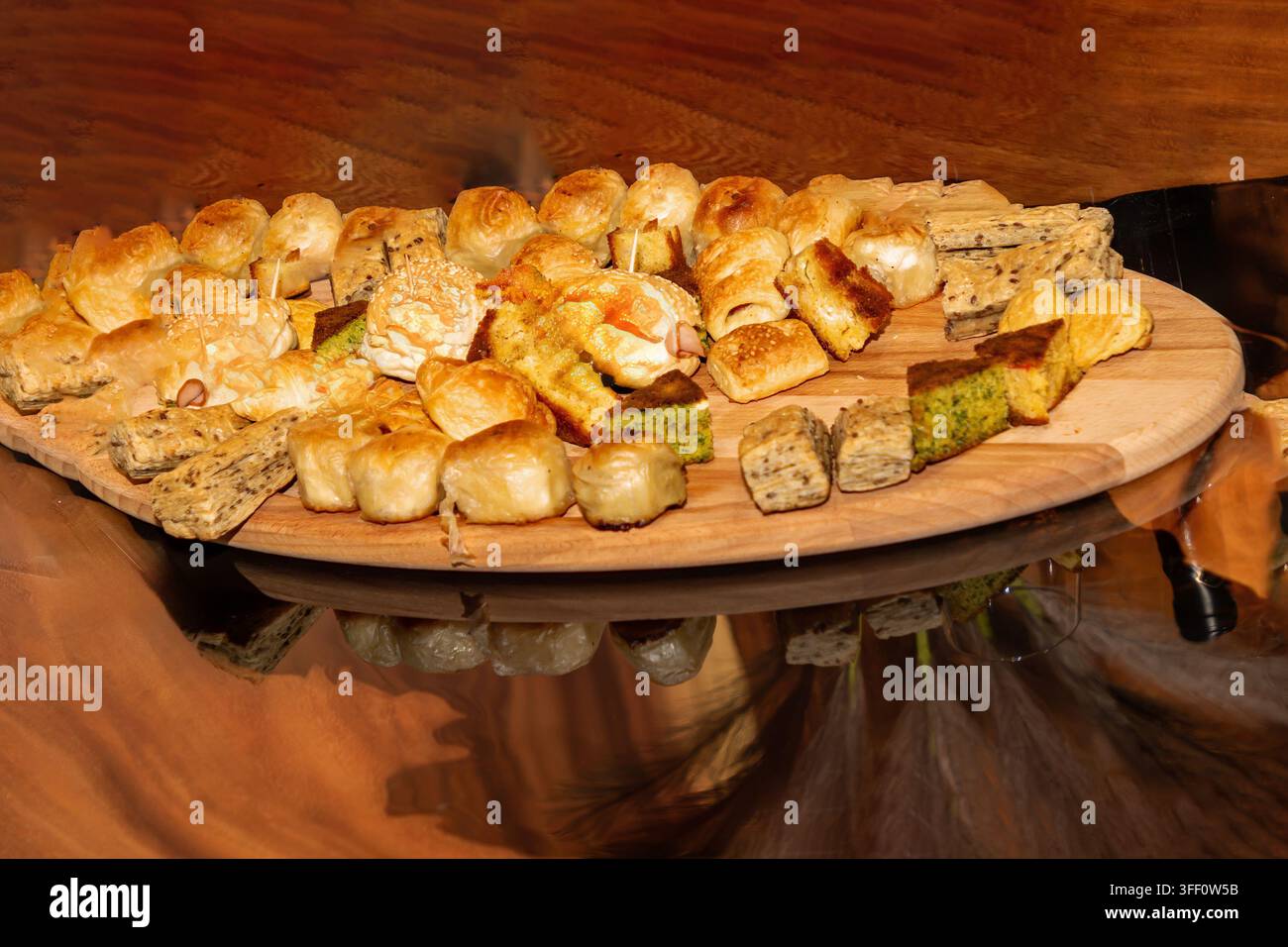 Kleine Gebäckhäppchen häufen sich auf einem Holzteller auf einer Party Stockfoto