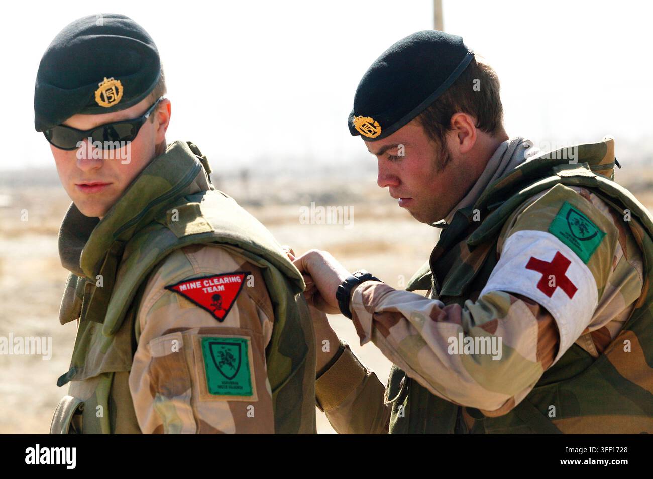 Militärmediziner unterstützt sorgfältig einen Kameraden bei der Anpassung der Taktischen Ausrüstung Stockfoto