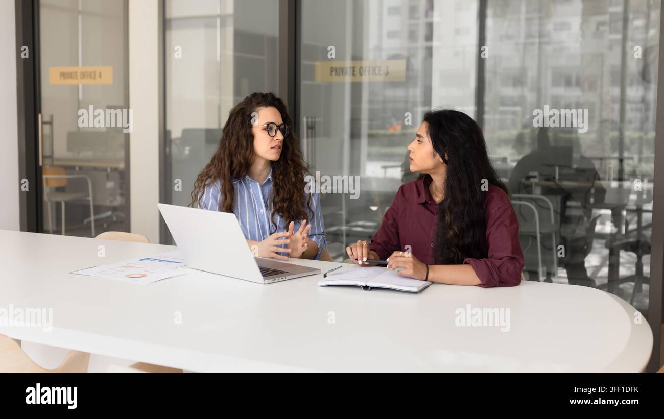Verschiedene junge erwachsene Geschäftsfrauen diskutieren Strategie im Besprechungsraum Stockfoto