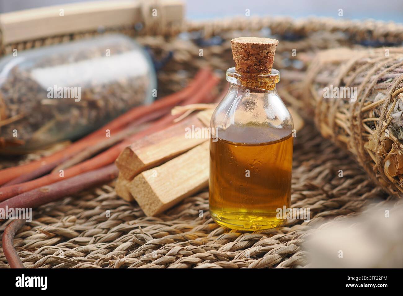 Palo Santo-Öl und Räucherstäbchen auf gewebter Matte für Aromatherapie und spirituelle Reinigungsrituale Stockfoto
