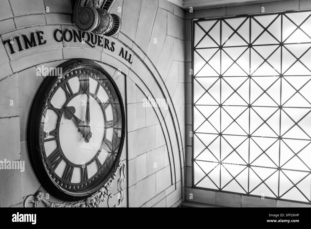 Eine große Wanduhr unter der Inschrift „ZEIT EROBERT ALLES“, umgeben von gewölbtem Mauerwerk Stockfoto
