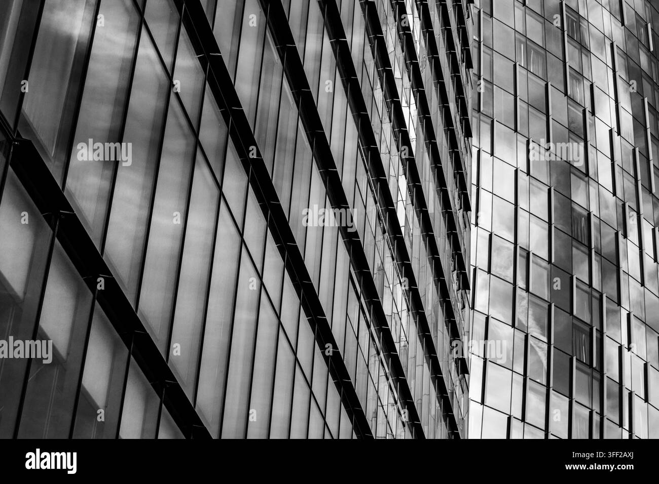 Schwarze und weiße moderne Wolkenkratzer mit reflektierenden Glasfassaden, die geometrische Linien, urbane Architektur und abstrakte Reflexionen zeigen. Stockfoto