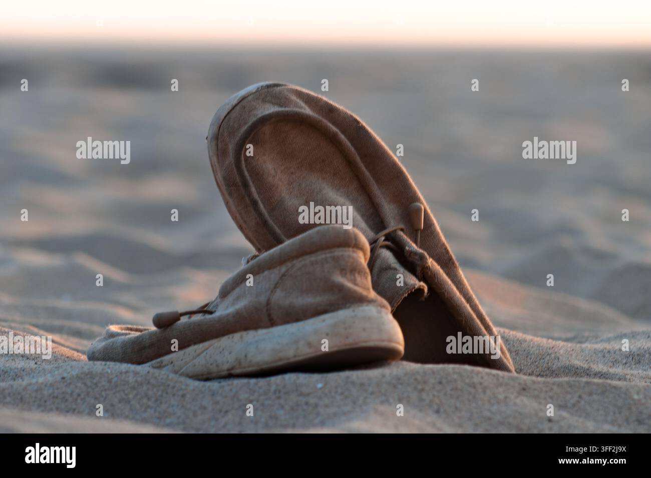 Ein Paar abgetragene braune Schuhe liegt im Sand in Hermosa Beach, Kalifornien. Stockfoto