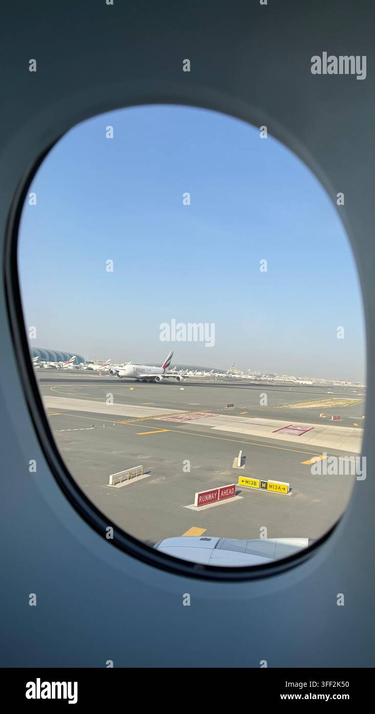 Durch ein Bullauge an Bord einer Airbus 380, während eine weitere Airbus 380 am Dubai International Airport in Dubai in den Vereinigten Arabischen Emiraten abhebt - Smartphone-aufgenommenes Stockfoto