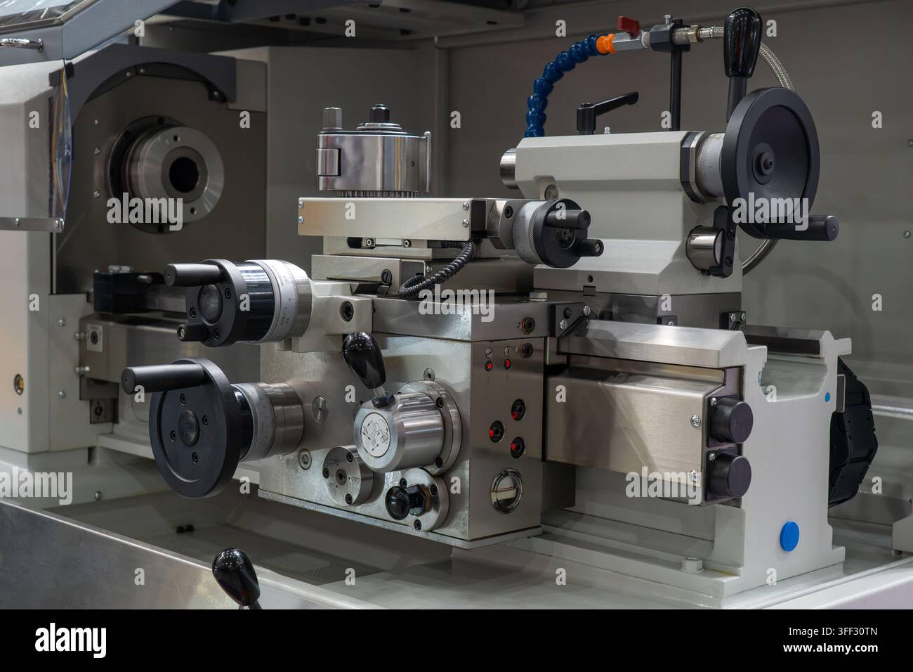 Nahaufnahme von Metallschleifmaschine, Schutzblech, Karosserie, Werkzeugschneide und Handrädern in einer industriellen Fertigungswerkstatt Stockfoto