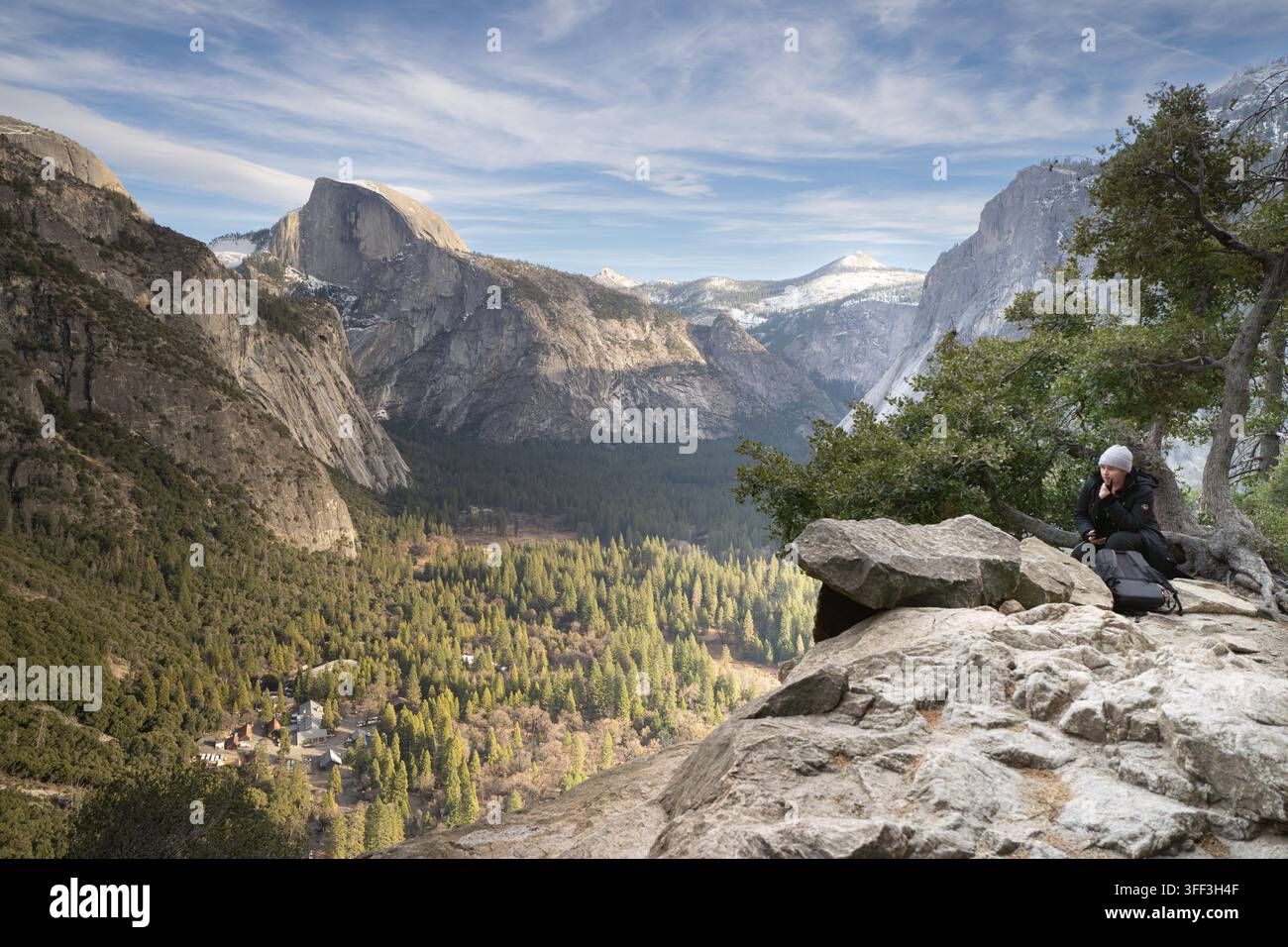 Ein Besucher verweilt am Inspiration Point oberhalb des Yosemite Valley, um den Winterblick auf den Half Dome und die schneebedeckten Sierra Nevada zu genießen. Stockfoto