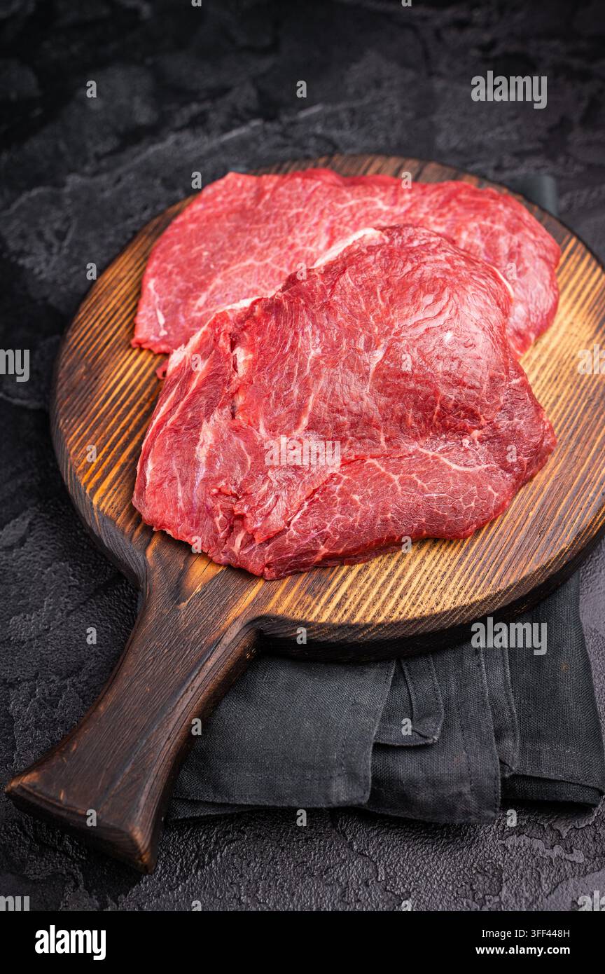 Metzgerbrett mit rohen Rinderwangen, ungekochtem Fleisch. Schwarzer Hintergrund. Draufsicht Stockfoto