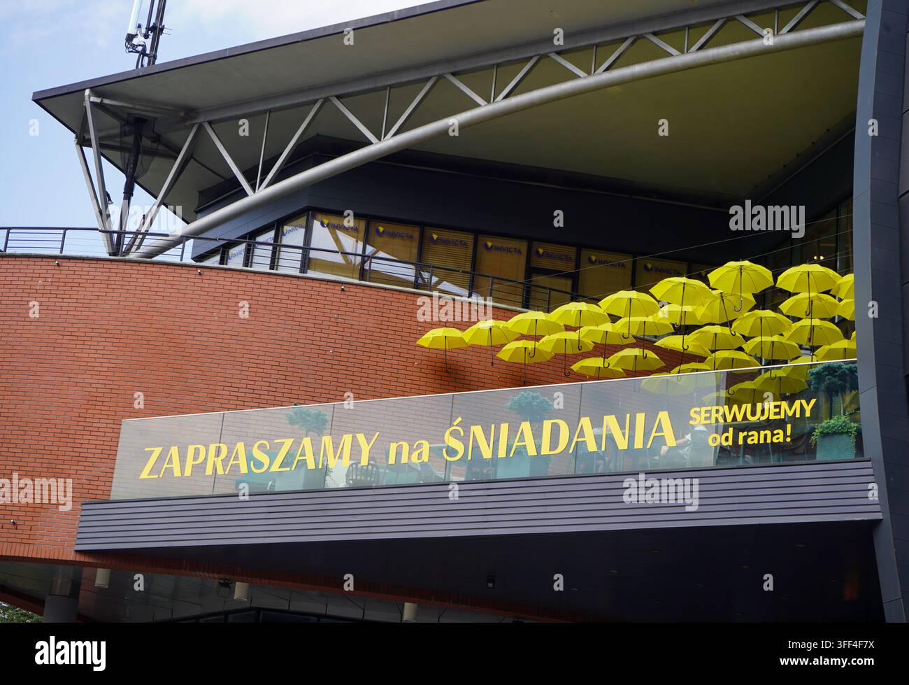 Außenarchitektonische Ansicht des Eingangs einer modernen Einkaufsmall, dekoriert mit hellen gelben Sonnenschirmen im Stadtzentrum von Danzig, Polen. Stockfoto