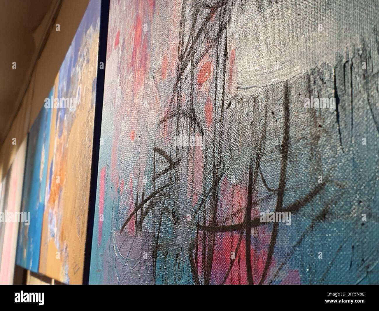 Nahaufnahme einer schrägen Ansicht von abstrakten expressionistischen Gemälden auf Leinwand, die in einer Galerieausstellung gezeigt werden. Das Bild im Vordergrund zeigt texturierte Schichten von Stockfoto