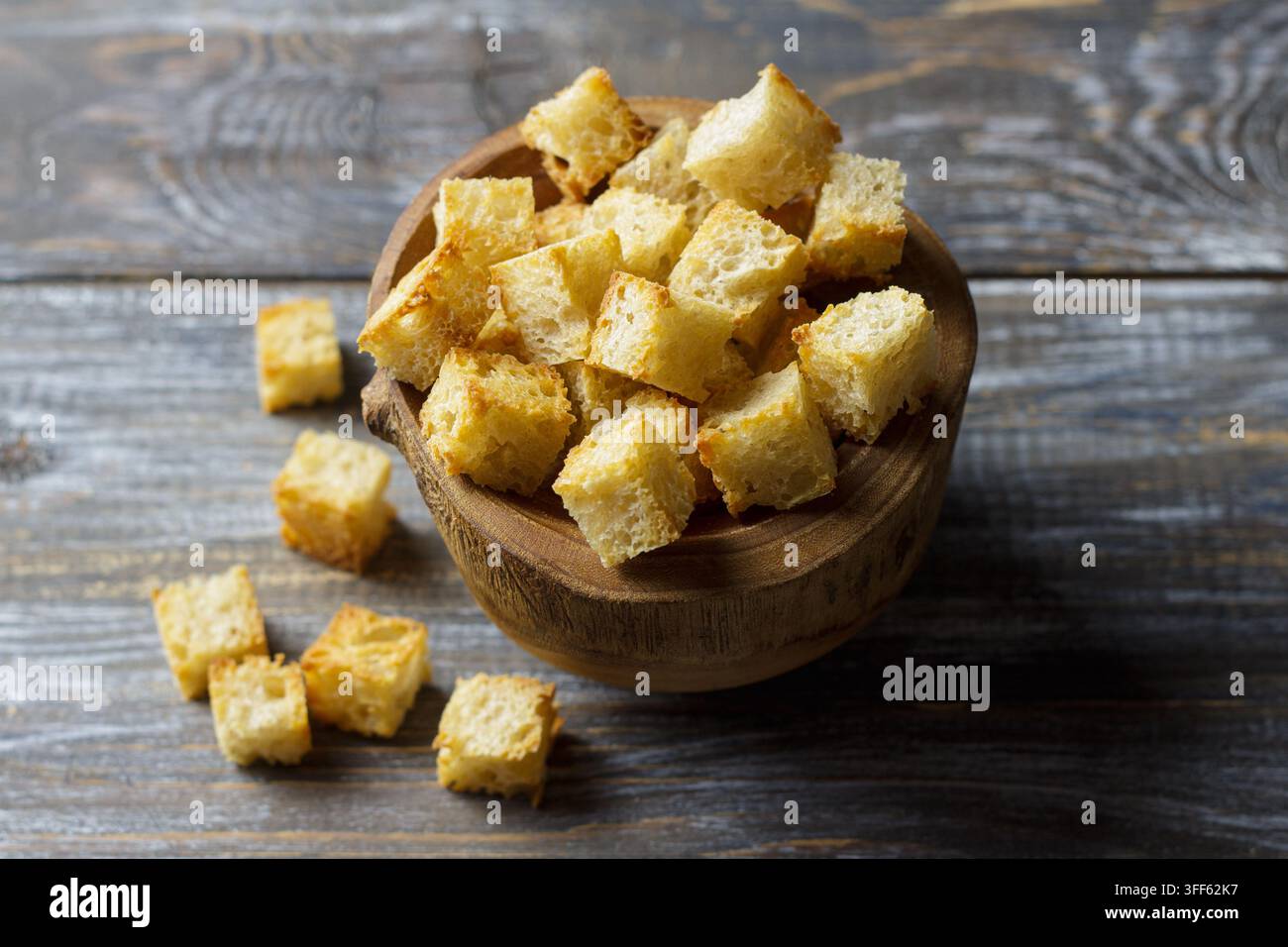 Hausgemachte Croutons in einer Holzschale auf einem rustikalen dunklen Holztisch Stockfoto