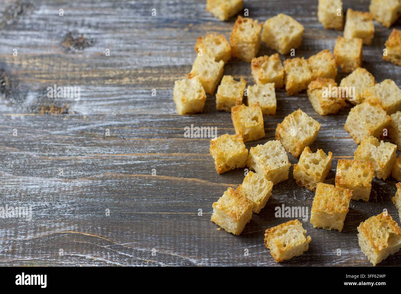 Verstreute goldene Croutons auf rustikalem dunklem Holztisch mit Kopierraum Stockfoto