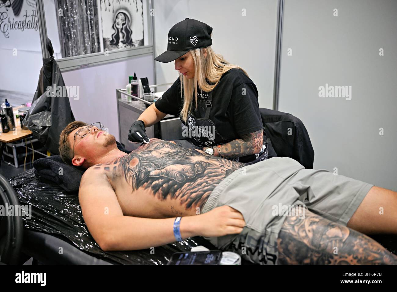 LONDON, UK. 06. Sep, 2026. Am letzten Tag der Big London Tattoo Show 2026 waren die Tätowierer von Diamond Heart Tattoo fast fertig mit einem Vollbrusttattoo, das sie live für ihren Kunden tätowierten. (Foto von 李世惠/See Li/Picture Capital) Credit: See Li/Picture Capital/Alamy Live News Stockfoto