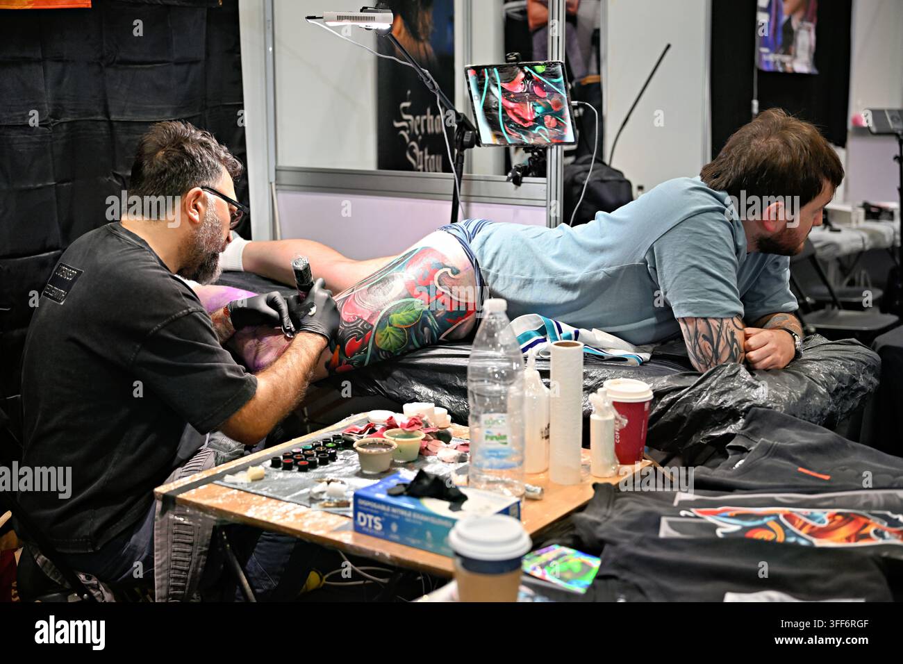 LONDON, ENGLAND - 06. September 2026: Am letzten Tag der Big London Tattoo Show 2026 war der Tätowierer Volkan Demirici Tattoo kurz davor, ein atemberaubendes Vollbein-Oberschenkel-Tattoo für seinen Kunden zu beenden, live vor der faszinierten Menge tätowierend. Die Atmosphäre war elektrisch, die Zuschauer waren von seinem Können und seiner Hingabe fasziniert, während er akribisch daran arbeitete, das komplizierte Design abzuschließen. Die Luft vibrierte vor Vorfreude, als die letzten Striche das Kunstwerk zum Leben erweckten und einen weiteren unglaublichen Moment in seiner bemerkenswerten Karriere markierten. (Foto von 李世惠/See Li/Picture Capital) Stockfoto