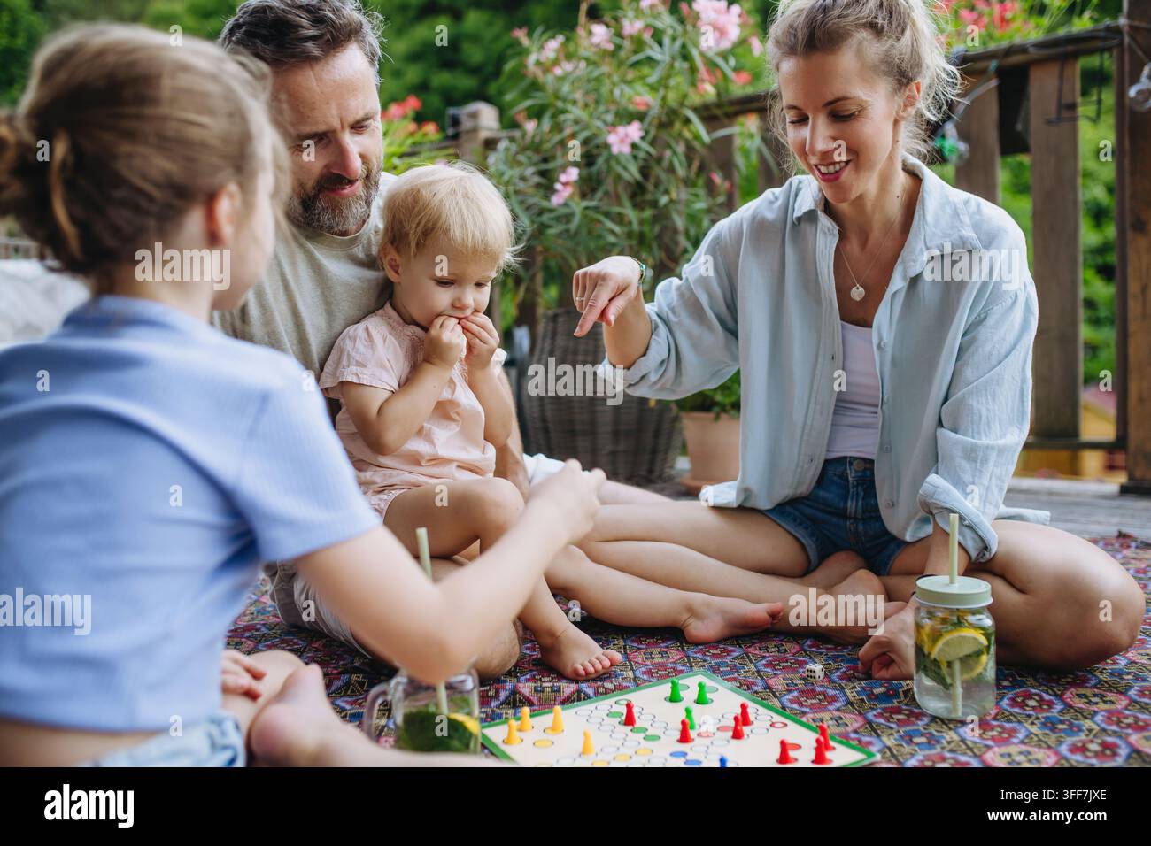 Familie genießt ein Brettspiel zusammen auf der Außenterrasse im Sommer. Stockfoto