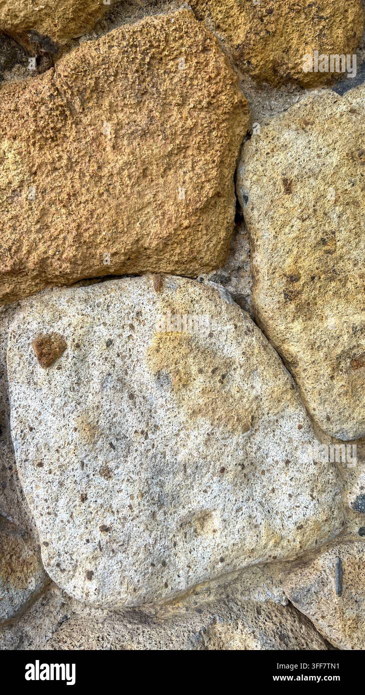 Naturstein-Wandtextur mit hellbraunen und grauen Steinen Stockfoto