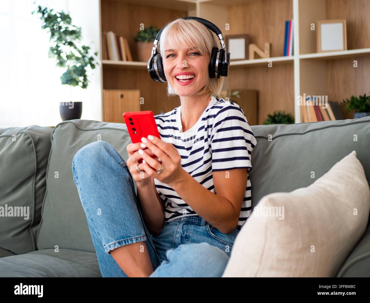 Entspannte Frau, die ihre Lieblingslieder streamt und Unterhaltung von ihrem Smartphone genießt. Stockfoto